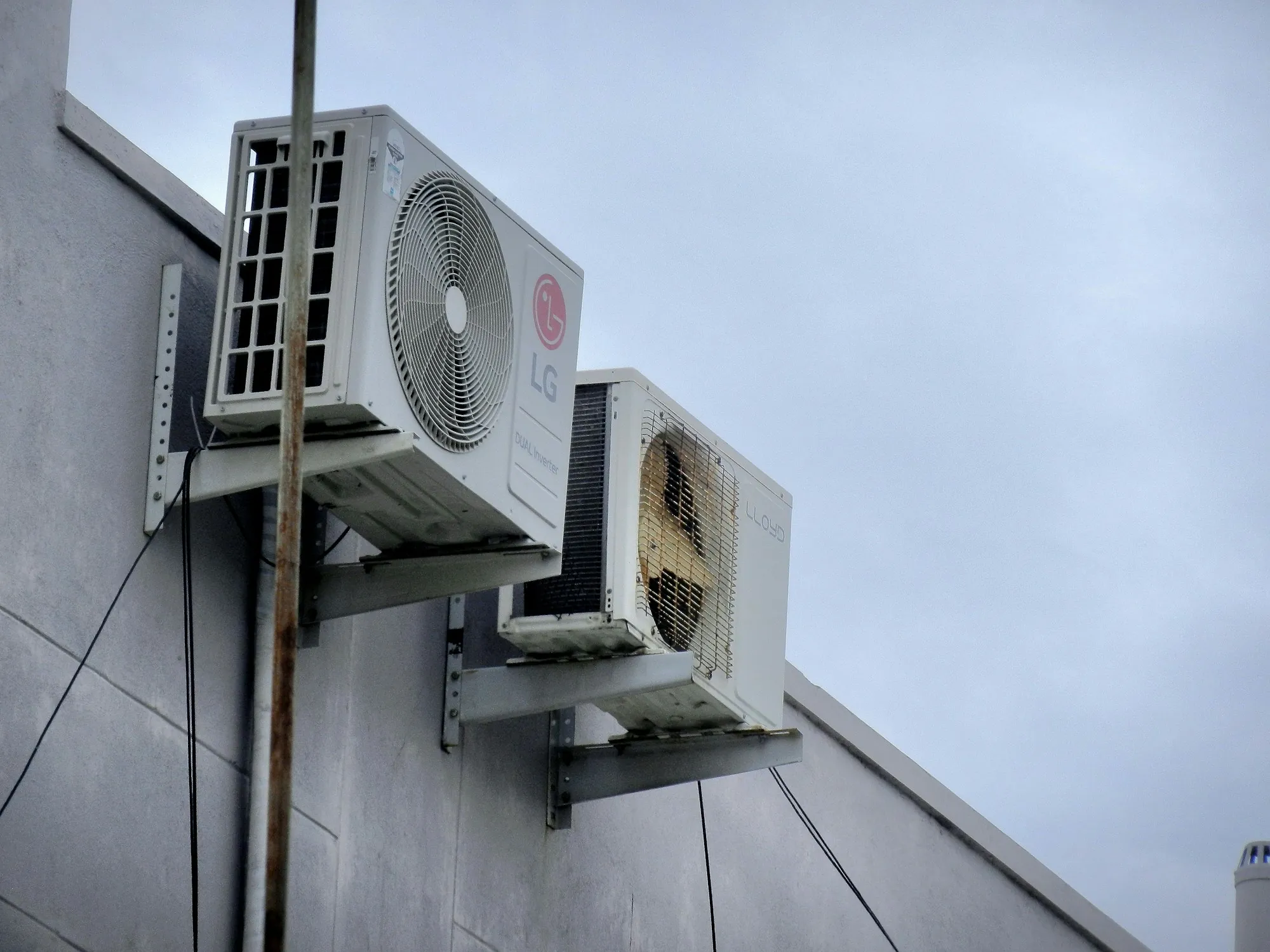 Two AC condensers on brackets high on a building wall